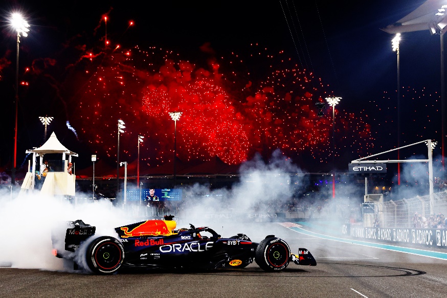 A race car on a track with fireworks in the background

Description automatically generated